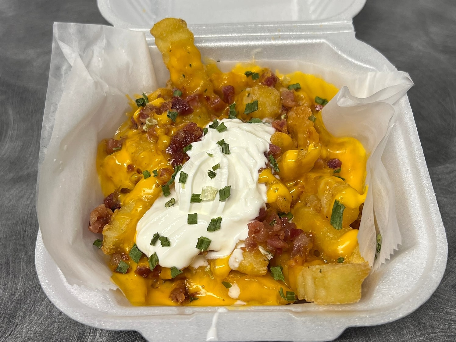 Loaded crinkle fries with cheese sauce, bacon, sour cream and chives