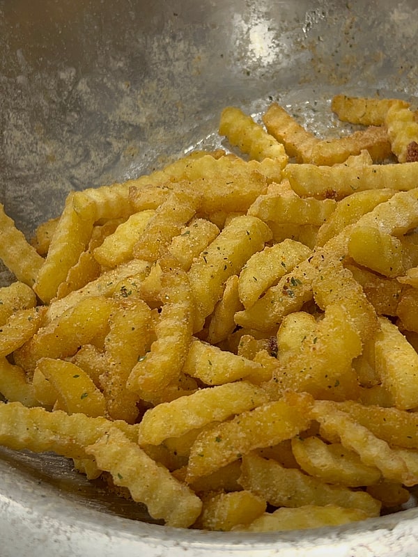 Fresh seasoned crinkle fries in a steel bowl