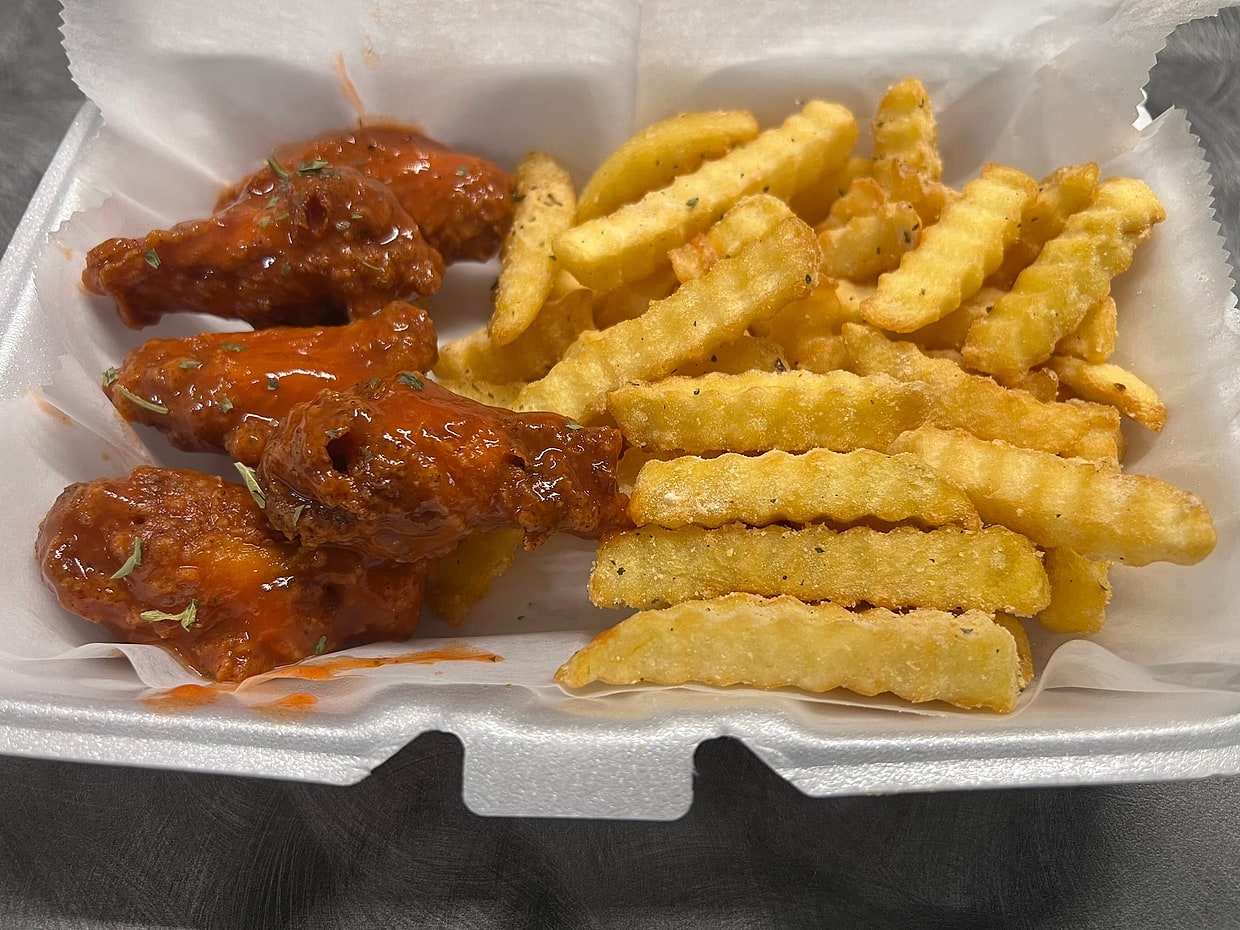Glossy buffalo wings beside seasoned crinkle fries