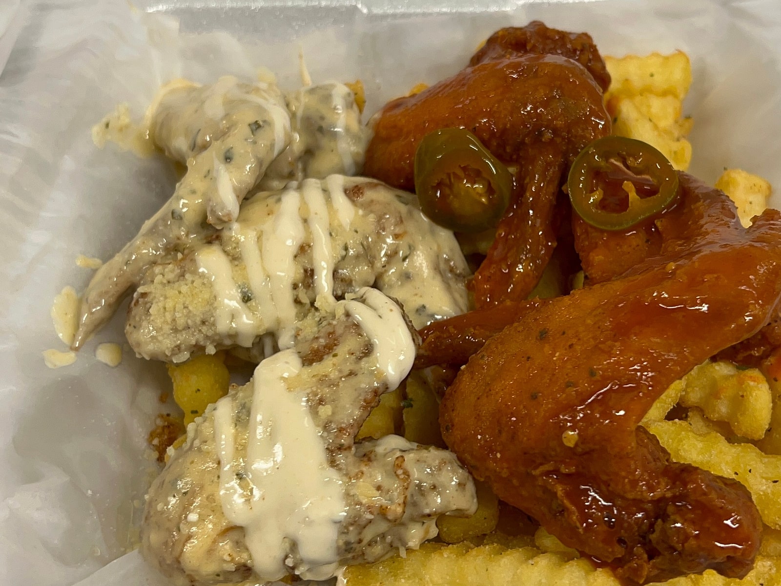 Whole wings in two sauces, garlic parmesan and buffalo with jalapeños, over crinkle fries